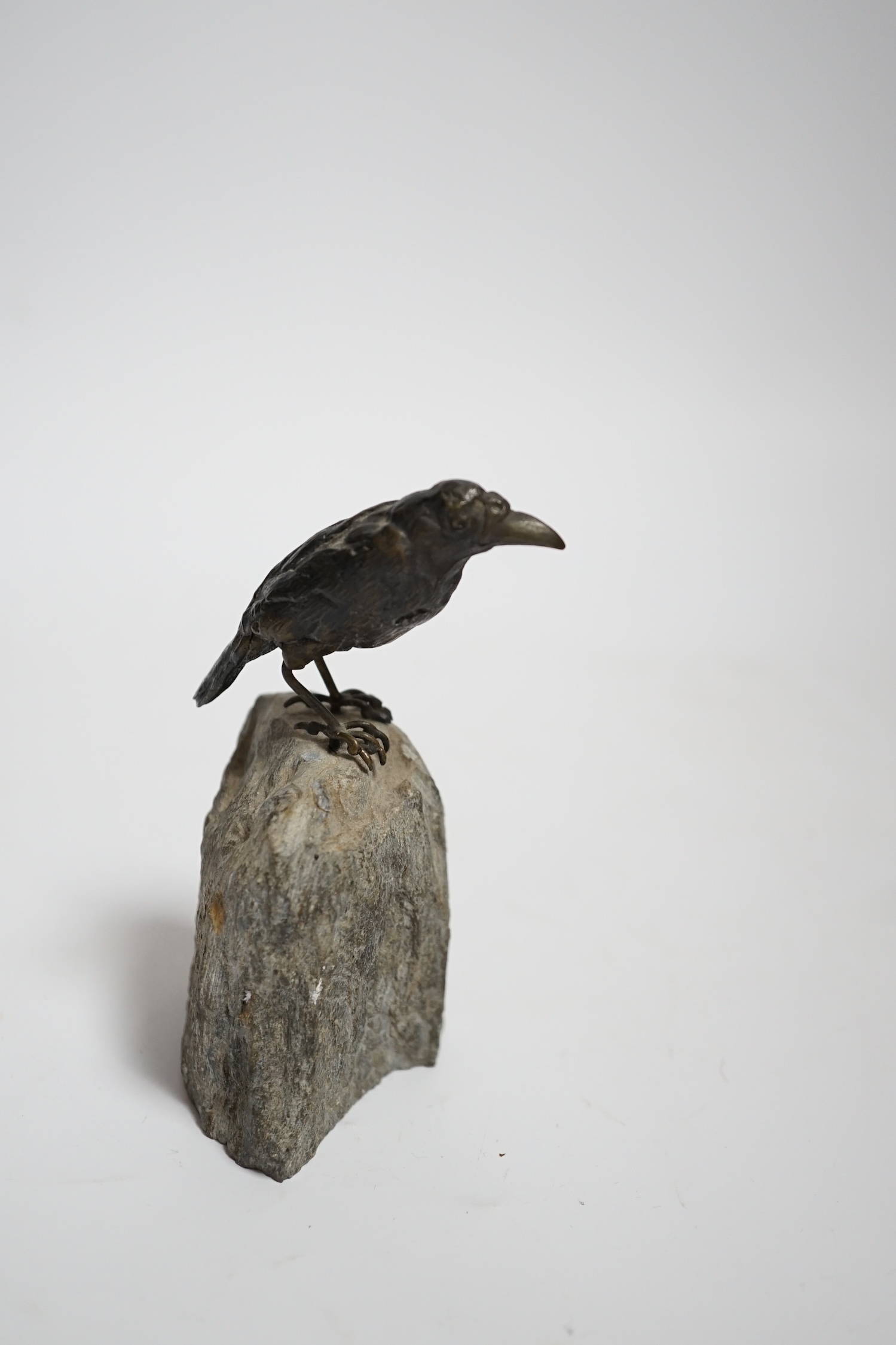 A cold painted bronze crow, raised on a stone base, 10cm high